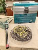 Plano tackle box, landing net, wire trap grouped on table