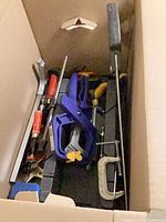 Box of clamps, screwdrivers, pry bar, saw