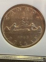 Reverse side of 1955 Canadian Voyageur dollar showing canoe design and date