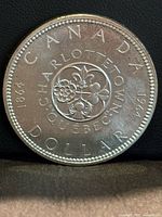 Reverse of 1964 Charlottetown-Québec silver dollar showing emblem, legends and dates