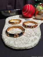All three enamel Joan Rivers hinged bangles displayed on fabric pad