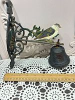 Side view showing bird figure, bracket detail, bell, and ruler for scale