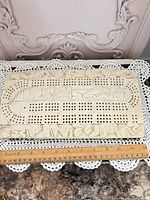 Top view of entire cribbage board with ruler showing length