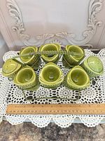 Full set on lace mat showing six egg cups, two shakers and metal rack