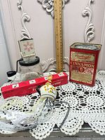Group shot showing cinnamon tin, grinder, food decorator box, ceramic tassel