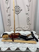 Full view of wooden puppet lying next to ruler with control rod attached