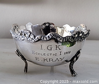 Exterior view showing engraved inscription, scalloped rim and tripod feet