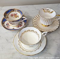 All three cup and saucer sets on marble surface