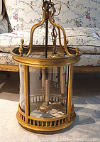 Full view of gilded cylindrical lantern on floor