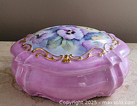 Lid side view showing pink glaze, pansy painting, gold scrollwork