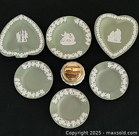 Seven Wedgwood dishes and lighter arranged on black background
