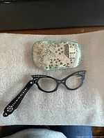 Spectacles unfolded beside embroidered pouch