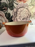 Side view of orange Le Creuset Dutch oven with handles