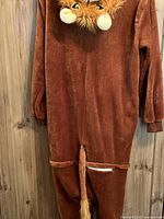 Back view of brown lion onesie showing tail, hood with lion face