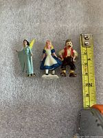 Front view of three Disney mini figurines with measuring tape for scale
