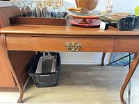 Front view showing desk, single drawer with brass pull, cabriole legs