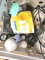 Basket containing GE LED bulb pack, loose LED bulbs, yellow flashlight, power strip and cables