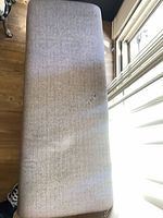 Top view of gray upholstered bench showing stain and woven texture