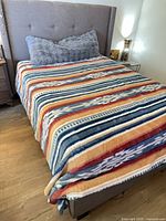 Front angled view of assembled gray wingback upholstered queen bed