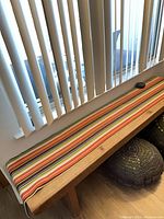 Bench with striped cushion on top, placed by window
