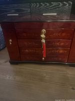 Front view of closed jewelry box with floral inlay and key in lock