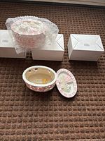Open jewelry box showing pastel exterior, interior mechanism and lid design; two sealed boxes and boxed unit with bubble wrap visible