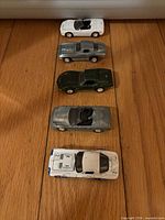 Top view of five toy cars aligned showing colours and styles
