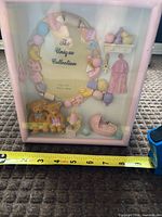 Front view of one baby-themed shadow box frame showing design and tape for scale