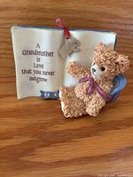 Front view of bear figurine leaning on open book with inscription and charm