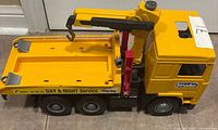 Full view of yellow Bruder tow truck, side profile