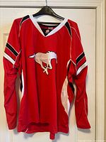 Front view of red Calgary Stampeders jersey on hanger