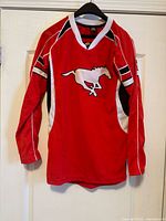 Front view of red Calgary Stampeders jersey hanging on hanger