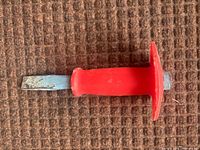 Entire chisel showing blade, red handle, and guard