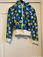 Front view of blue abstract circle print zip hoodie hanging