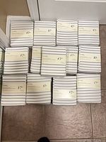 Stack of 13 packaged grey and white striped organic flannel crib sheets