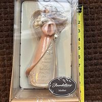Boxed Mother ornament figurine beside tape measure