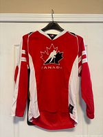 Front view of red Team Canada hockey jersey on hanger
