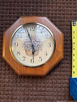 Front view of octagonal wood wall clock showing dial and hands