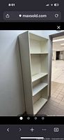 Tall white bookcase against wall showing shelves