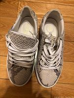 Top view of both sneakers showing snakeskin pattern, laces, and interior branding