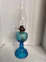 Full view of blue pressed glass oil lamp with clear chimney