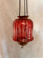 Close view of cranberry glass shade showing color, ribbing and base hardware