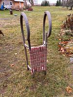 Full view of tall wooden sleigh standing on grass