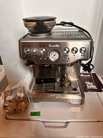 Front view of Breville espresso machine with accessories placed on drip tray and beside unit