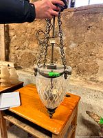 Full view of chandelier held up, showing cut glass shade, chains and canopy