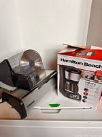 Overall view showing boxed Hamilton Beach coffee maker with Cuisinart slicer