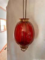 Full view of cranberry glass hall lamp suspended by chains