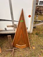 Full view of triangular wooden tree panel leaning against trailer with support pieces beside