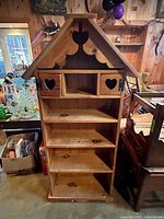 Front view showing full house-shaped pine bookcase with pitched roof and shelves