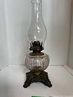 Full view of antique oil lamp showing chimney, font and base